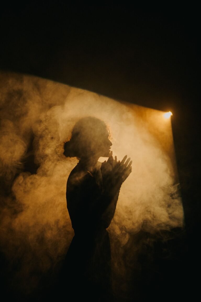 Silhouette of a person standing in warm light surrounded by mist